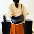 Minimalist black leather dumpling crossbody bag shown on model for size and fit - Black