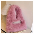 Primer plano del bolso de peluche rosa con bolsillo de cremallera sobre pila de libros - Rosa Roja