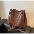 Borsa a secchiello vintage marrone in pelle con tracolla a nodo su divano - caffè