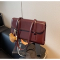 Detail of vintage burgundy shoulder bag with glossy finish and cute plush bear charm - Burgundy