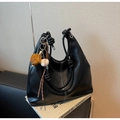 Dettaglio della borsa tote in pelle nera con cuciture a contrasto e ciondolo da baseball - Con Ciondolo / Nero