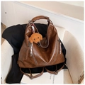 Brown vintage faux leather tote bag and backpack with a plush puppy charm on a sofa - With Charm / Brown