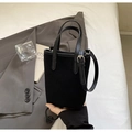 Gros plan sur le sac seau noir mat avec poignée texturée et boucle en métal argenté - Noir avec pendentif
