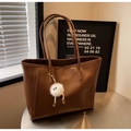 Große dunkelbraune Leder-Shopper-Tasche mit weißem Plüsch-Anhänger auf Metalltisch - Braun (Mit Weißem Anhänger)
