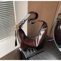 Dark brown glossy crescent bag with baseball charm on books in a warm aesthetic room - Coffee with Pendant