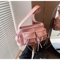 Detailweergave van roze baguette tas met strik, zijzakken en glanzende geplooide textuur - Roze