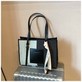 Detalle de bolso tote de lona y cuero con cinta de seda sobre maleta plateada - Negro y Blanco
