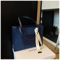 Detalle de un bolso tote de mezclilla con parche de cuero y una elegante cinta de letras - Azul oscuro
