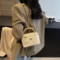 Weiße gesteppte Vanity Bag mit Kamelien-Ornament und goldener Kette in der Hand - Weiß