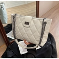 Close-up of white quilted tote bag featuring black chain straps and metal twist lock detail - White