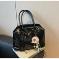 Detail einer schwarzen Kunstledertasche mit Gürtelschnalle und einem Plüschschaf-Anhänger - Mit Anhänger / Schwarz