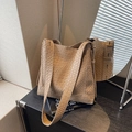 Elegante borsa a spalla intrecciata kaki in stile hobo su una libreria - Cachi