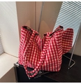 Detail of red and white checkered plush tote bag with silver buckle on a black cabinet - Red Check