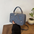 Blaue Denim Umhängetasche mit silbernen Nieten und Trageriemen in Lifestyle-Kulisse - Denim / Dunkelblau
