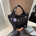 Black quilted handbag with white embroidered bows and a purple floral charm - Black