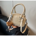 Dettaglio borsa beige in ecopelle con texture morbida e ciondolo a forma di orsetto - Bianco Sporco
