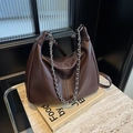 Braune Leder-Schultertasche in Halbmondform mit silberner Kette auf Marmor - Kaffeebraun