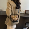 Bolso tipo cubo con estampado de leopardo, ribete de cuero negro y detalles dorados - Negro