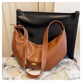 Makro-Detail der karamellfarbenen Halbmond-Tasche mit matter Ledertextur und goldener Hardware - Braun