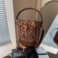 Bolso tipo cubo con estampado de leopardo, asas de cuero marrón y cierre dorado - café