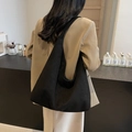 Borsa hobo nera minimalista in tessuto scamosciato indossata da una modella in un caffè - Nero