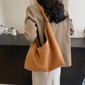 Caramel suede large hobo tote bag worn by a model in a minimalist cafe setting - Brown