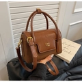 Detail of dark brown vintage faux leather handbag with gold logo and cylindrical handle - Brown