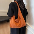 Große Shopper-Tasche aus Wildleder in Karamellbraun am Modell in minimalistischem Raum - Rotbraun