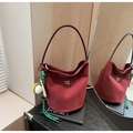 Dettaglio borsa a secchiello bordeaux scamosciata con ciondolo da baseball e logo oro - Con Ciondolo / Rosso