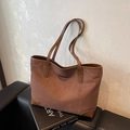 Braune Shopper-Tasche aus Wildlederimitat mit schmalen Henkeln auf einem Ledersofa - Braun