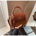 Dettaglio macro della borsa patchwork in pelle marrone con scritte in metallo dorato PAN TOR - Marrone
