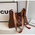 Close-up of brown quilted puffer bag with broad woven strap and cloud tassel detail - Coffee