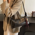 Retro black leather underarm bag with decorative woven pendant worn by a model - Black
