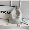 Detailed macro view of cream quilted mini backpack with soft puffer texture and silver zippers - White