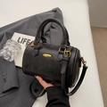 Matte black leather cylindrical pillow bag with gold hardware and hand-held strap - No Pendant / Black