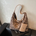 Große Shopper-Tasche mit Leopardenmuster und passendem braunem Etui auf schwarzem Sofa - Khaki