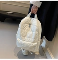 Detail of a beige quilted puffer backpack featuring silver zippers and padded texture - White
