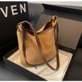 Dettaglio della borsa hobo in pelle scamosciata marrone e shearling crema in una confezione - Marrone
