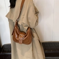 Vintage braune Hobo-Schultertasche mit Schnalle, kombiniert mit einem beigen Trenchcoat - Gelbbraun