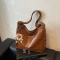 Braune Vintage Hobo-Tasche mit Löwen-Plüsch-Anhänger auf Ledersofa-Hintergrund - Mit Anhänger / Braun