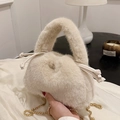 Bolso tipo cubo de felpa blanco crema con textura suave y cadena dorada en la mano - Caqui