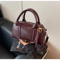 Detailed shot of dark burgundy Boston bag with gold hardware and top zipper closure - Burgundy