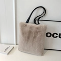 Sac cabas en peluche beige avec anses en cuir noir sur un bureau blanc épuré - Khaki