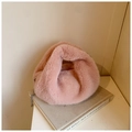 Gros plan d'un sac à main rose en fausse fourrure avec poignée nouée et chaîne argentée - Rose