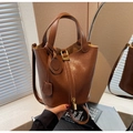 Close-up of retro brown leather bucket bag with gold lock and smiley face pendant - Brown