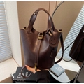 Detail of dark brown leather bucket bag with gold padlock and smiley face charm decoration - Coffee