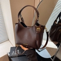 Dunkelbraune Lederbeuteltasche mit goldener Hardware und Tragegriffen im Lifestyle-Set - Braun
