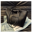 Close-up of black leather tote bag with zipper detail on denim and magazine - Black