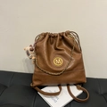 Vintage brown leather bucket backpack featuring a gold M logo and decorative metal chain - With Charm / Brown