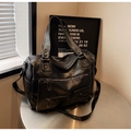 Detalle de bolso de viaje vintage en cuero negro con varios bolsillos en mesa de metal - Negro